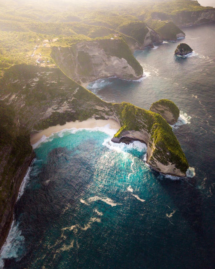 Stunning aerial view of Balis coastline with turquoise waters and lush cliffs.